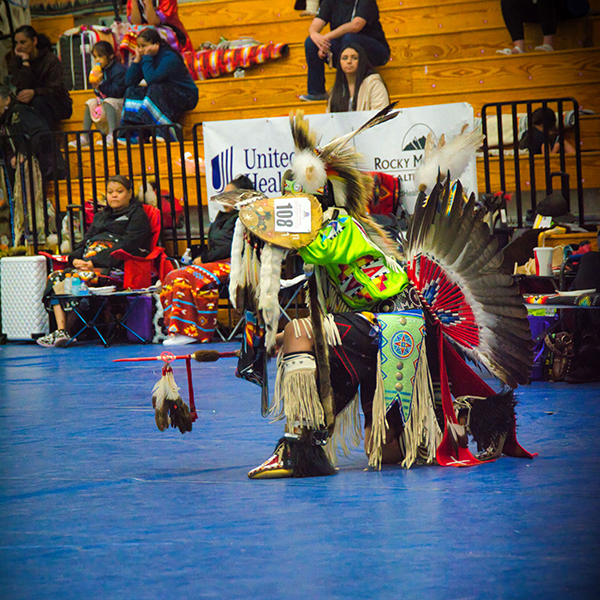 Dancer in traditional regalia kneeling