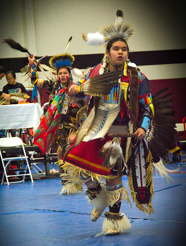 Two Native American dancers in traditional regalia performing