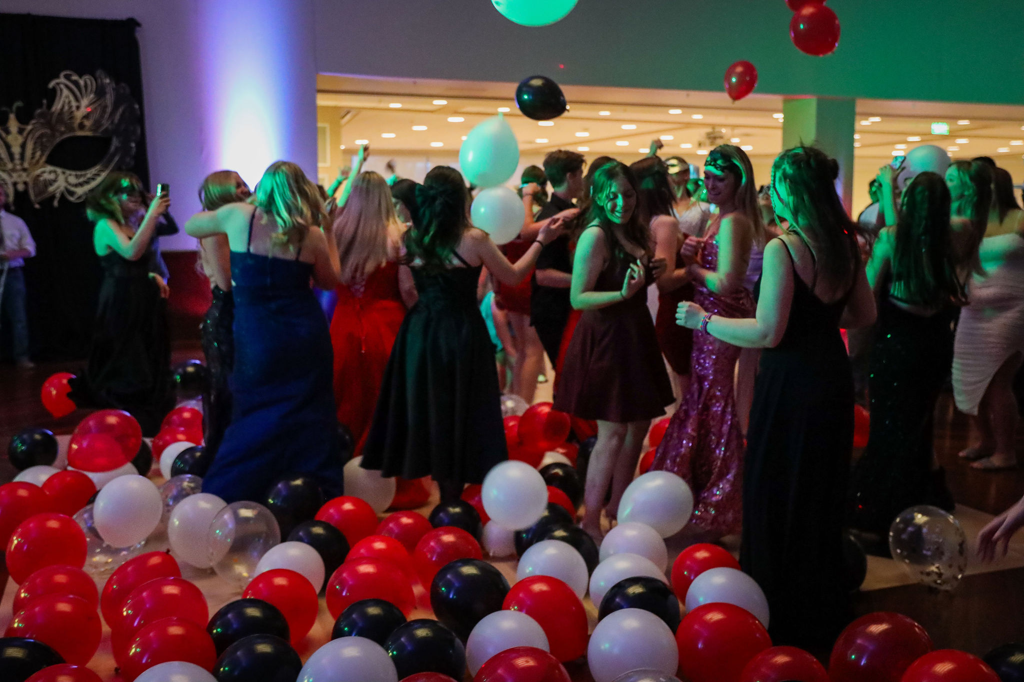 Students dancing at masquerade prom with balloons