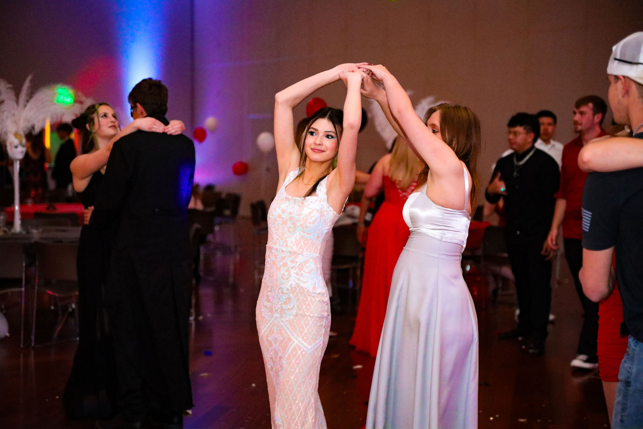 Two young women dancing together at masquerade prom