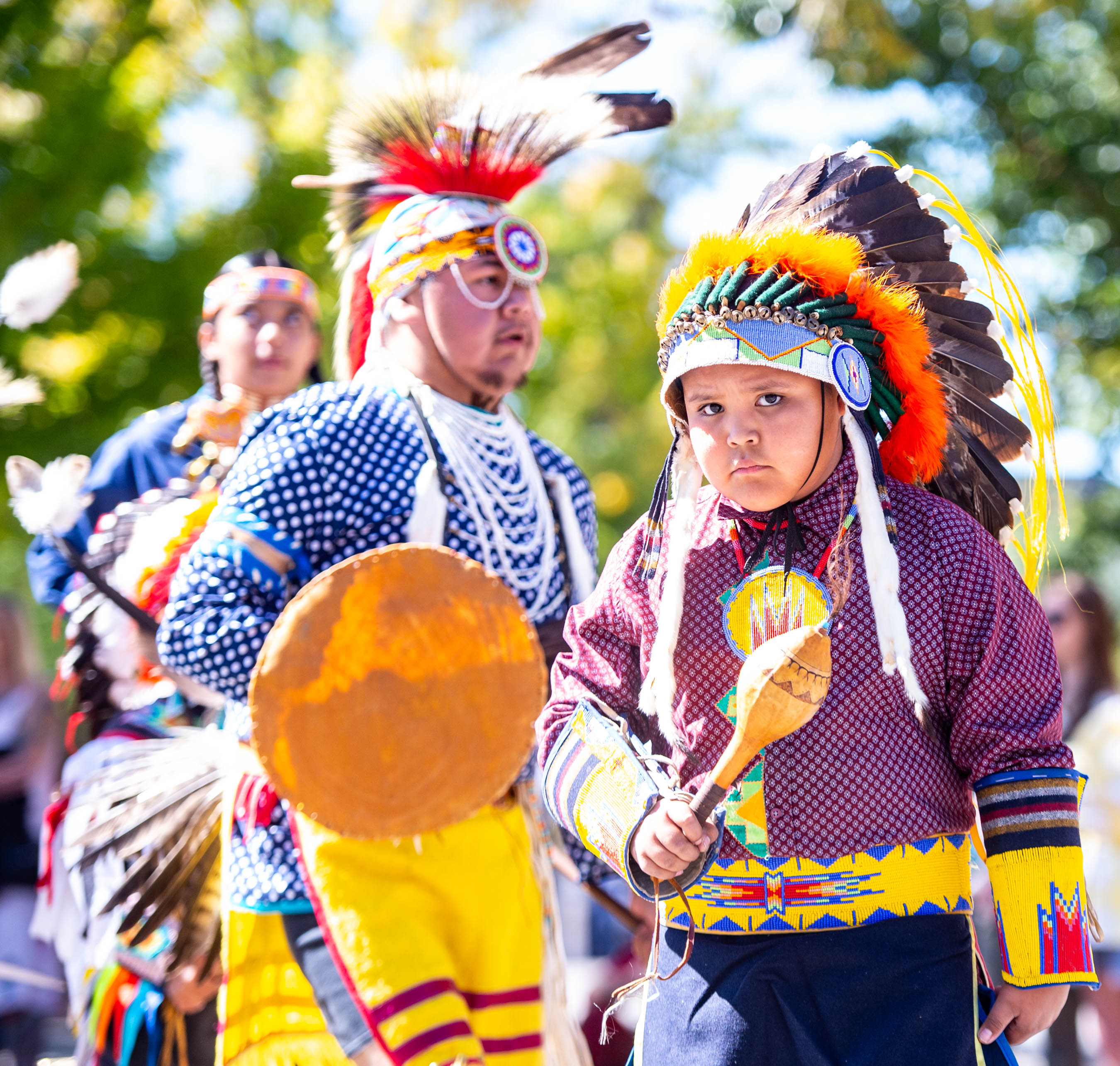 Young Native American dancer in traditional regalia holding rattle