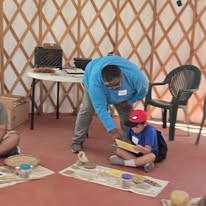 Adult helping child with craft project in yurt
