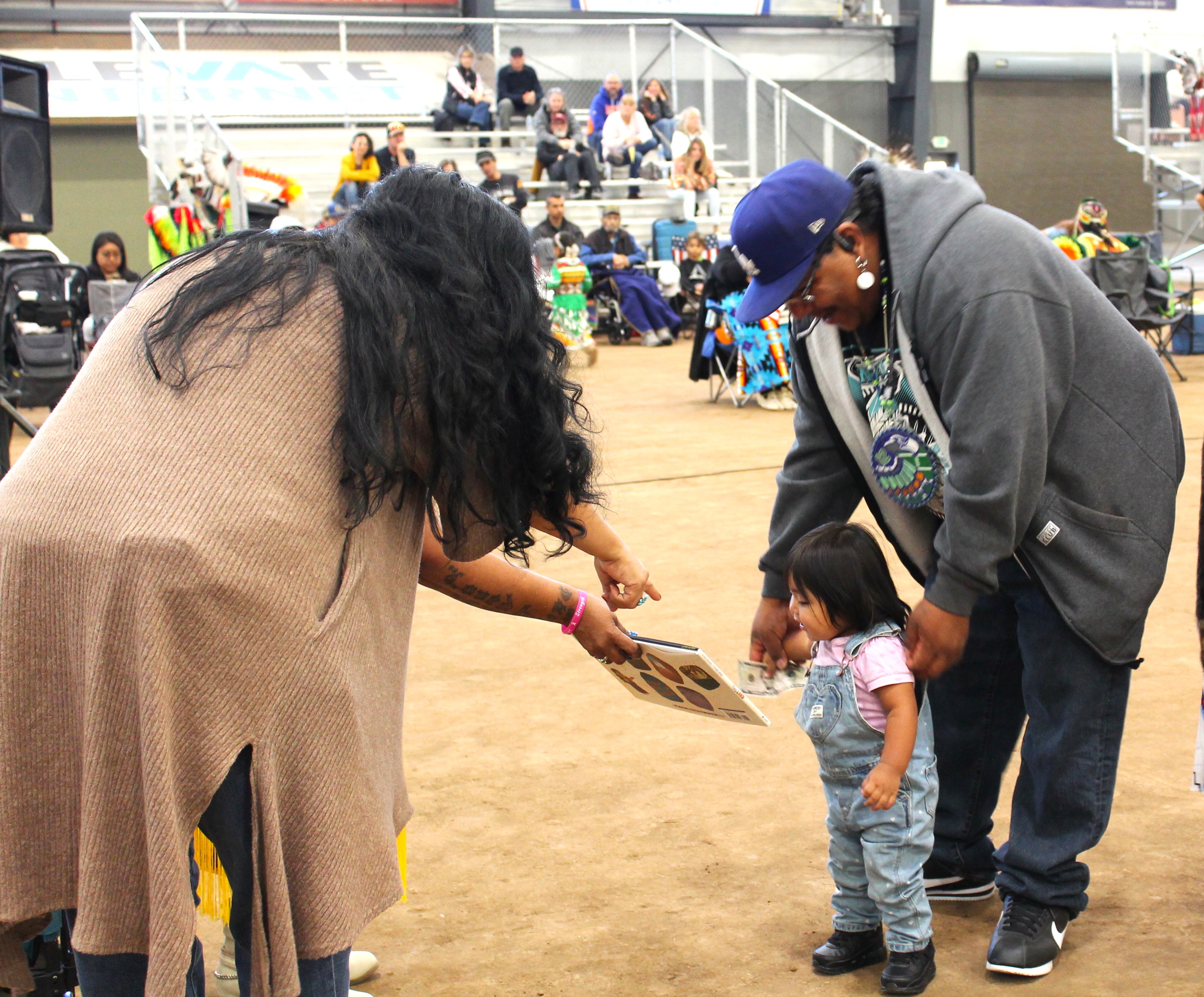 Woman showing a book to a toddler and man